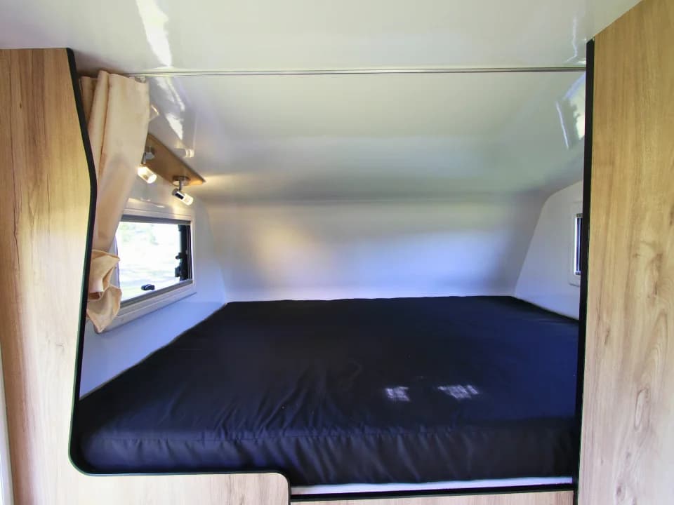 2026 Made by Smidge Long Weekend — over-cab bed fully extended, sleeping position for two adults