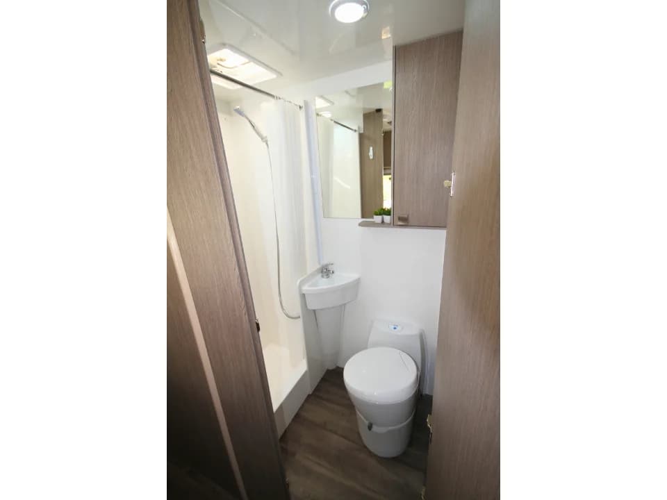 Saxby F-2 interior — separate bathroom with shower recess, Thetford cassette toilet, recessed basin and vanity mirror
