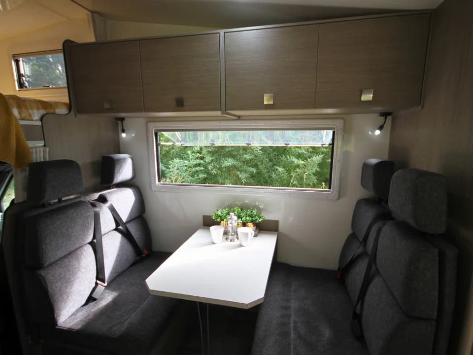 Saxby F-2 interior — rear dinette with facing bench seats, seatbelts and overhead storage
