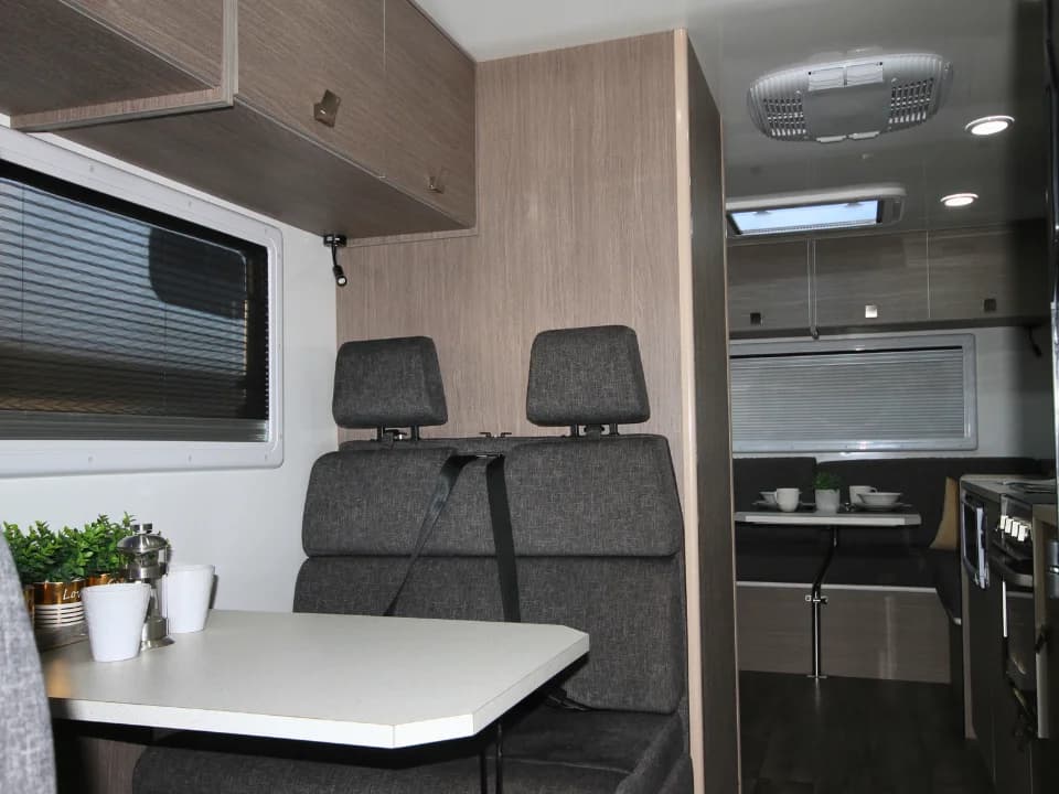 Saxby F-2 demo interior — rear bench seats and fold-down table looking forward through cab walkthrough