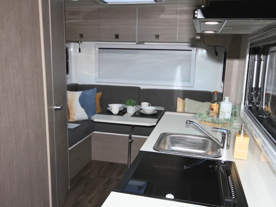 Saxby F-2 demo interior — kitchen bench with microwave, sink, cooktop and overhead cabinets