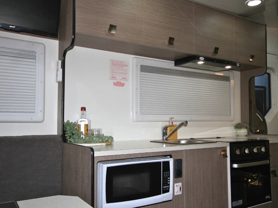Saxby F-2 demo interior — kitchen sink and cooktop with club lounge seating beyond