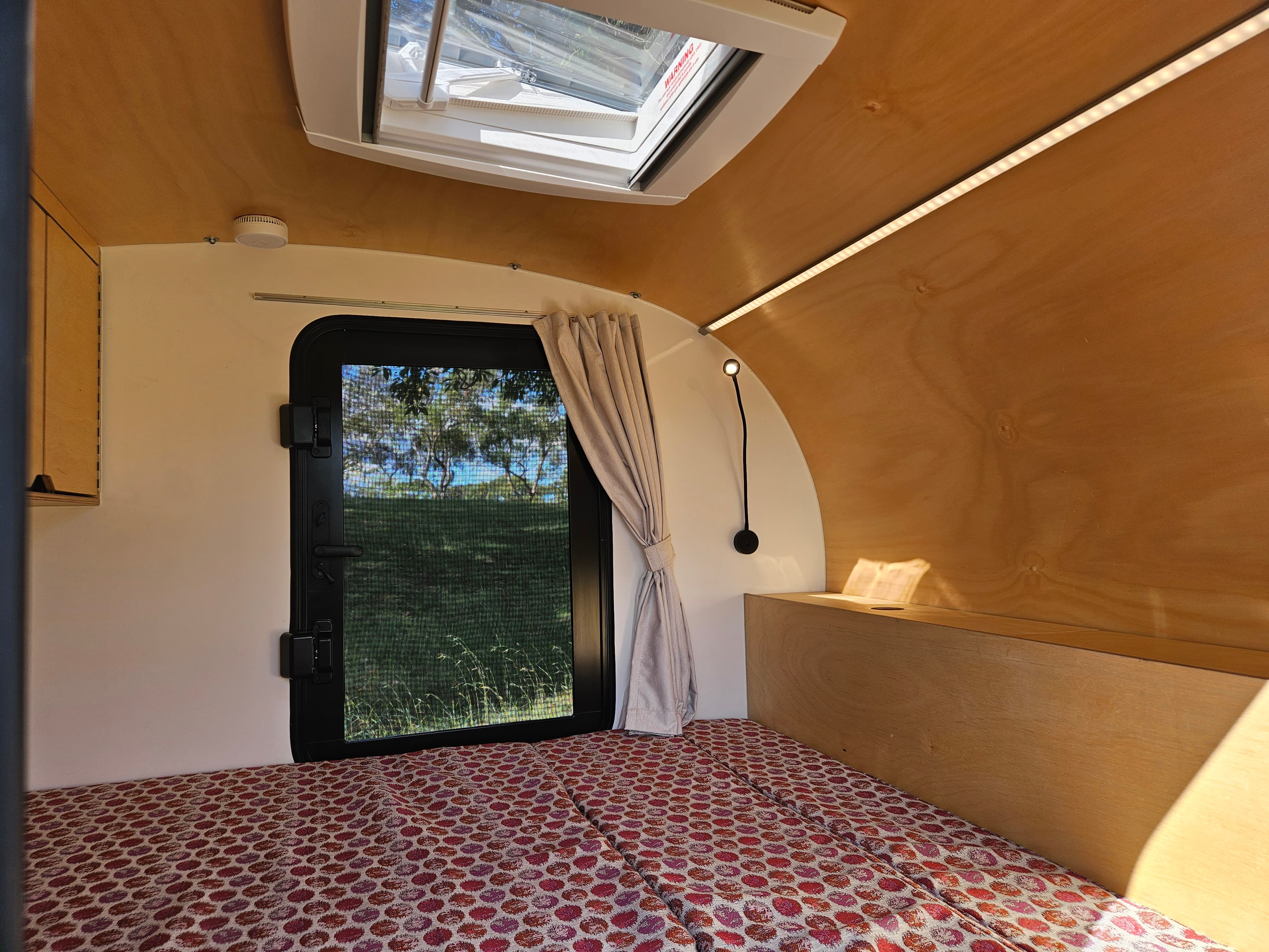 2024 Smidge Breeze interior — queen-size cabin with overhead skylight, LED strip lighting, and block-out curtain