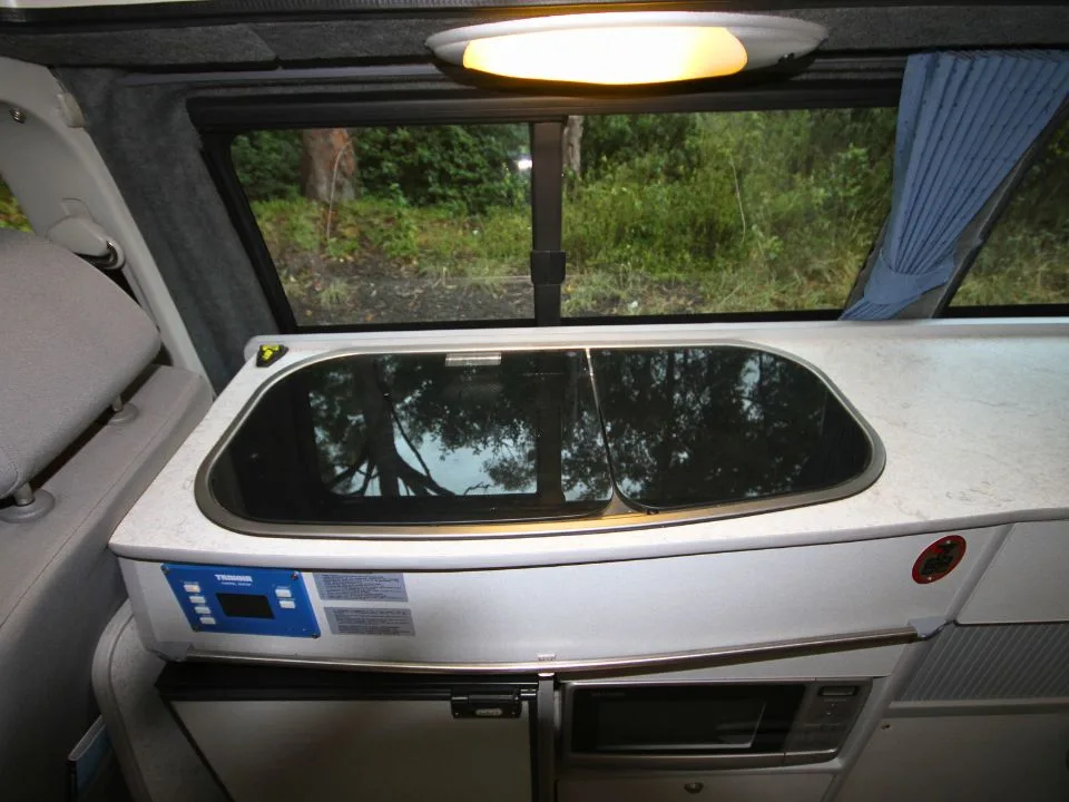 2007 Trakka Trakkadu T5 campervan — kitchen bench with Trakka control panel, fridge and microwave below