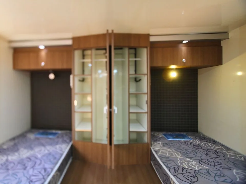 2011 Suncamper Sydney motorhome — interior twin beds with glass-fronted display cabinet and LED reading lights