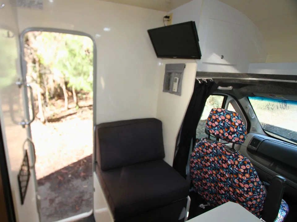 2011 Suncamper Sydney motorhome — interior looking forward with lounge seat and wall-mounted TV