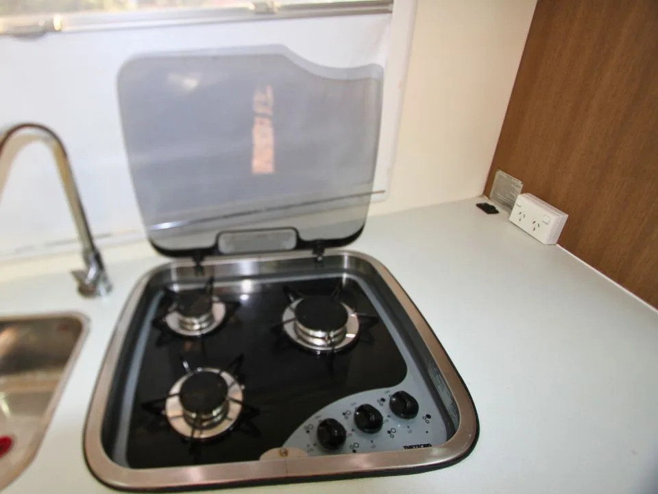 2011 Suncamper Sydney motorhome — interior 3-burner Thetford gas cooktop with glass lid open