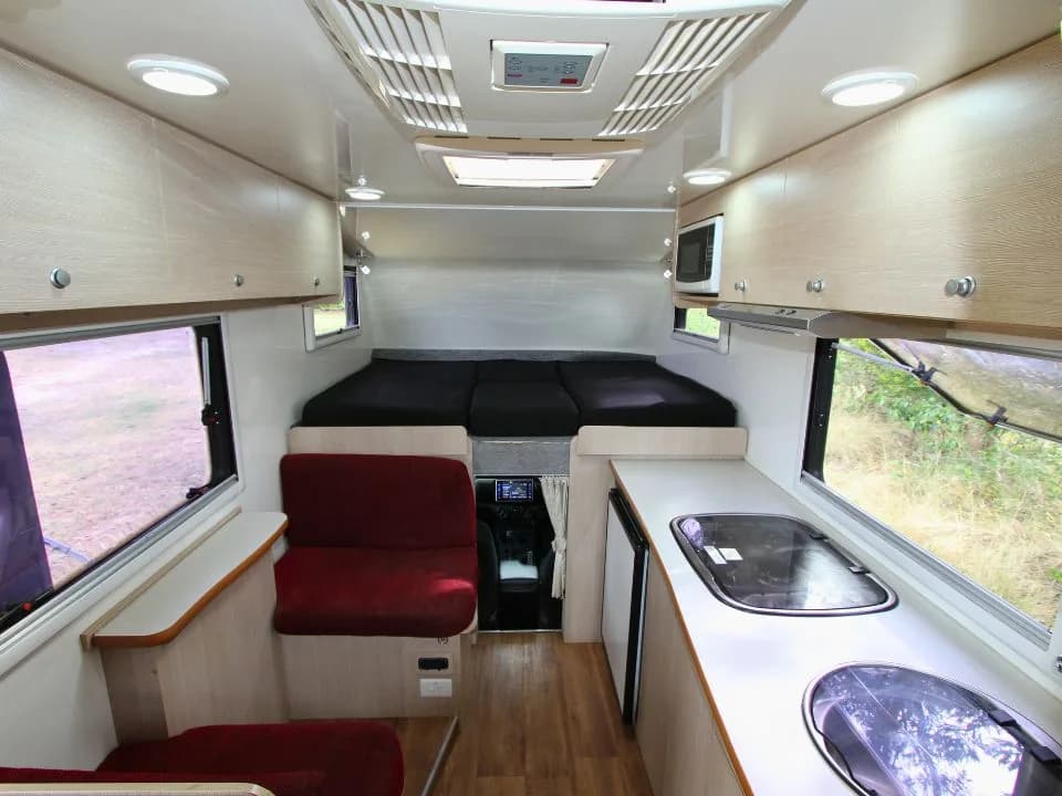 2015 Suncamper Sherwood 4x4 Twin motorhome — interior over-cab twin beds with dinette and cab view