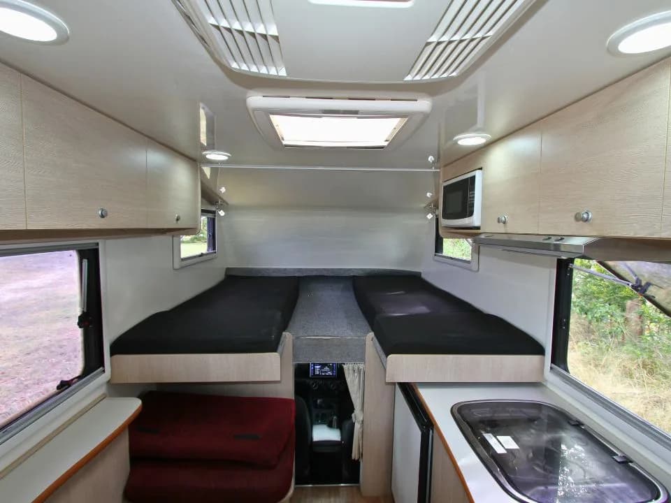 2015 Suncamper Sherwood 4x4 Twin motorhome — interior over-cab twin beds with kitchen glimpse