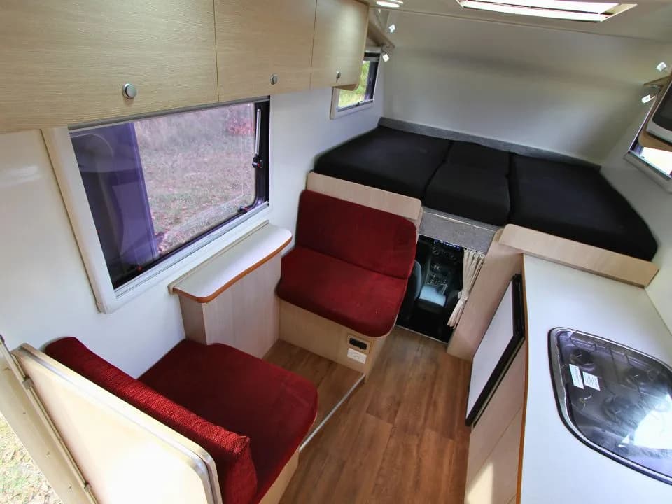 2015 Suncamper Sherwood 4x4 Twin motorhome — interior overview showing over-cab twin beds and dinette
