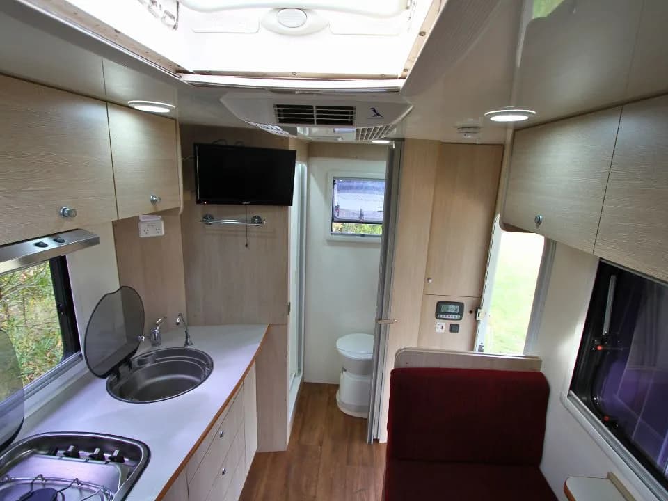 2015 Suncamper Sherwood 4x4 Twin motorhome — interior kitchen overview with TV and bathroom in background