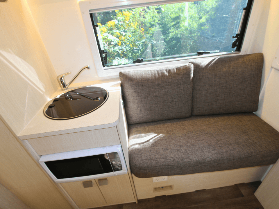 2024 Suncamper Sherwood E-2 interior — lounge seating with kitchen bench and microwave